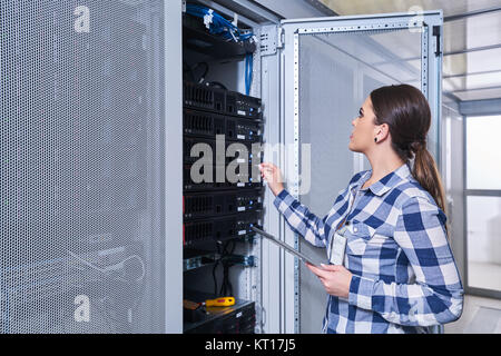 female technician working on server maintenance in white server room Stock Photo