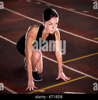 Beautiful female sprinter waiting for the start on a runway Stock Photo
