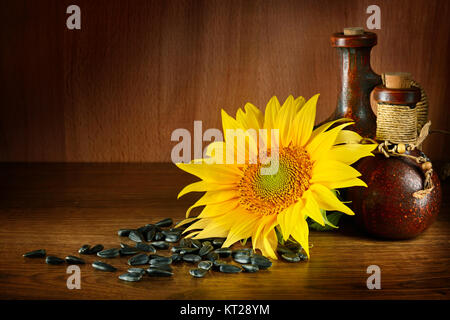 Vegetable oil in ceramic ware and sunflower seeds on wooden background. Healthy food. Free space for text. Stock Photo