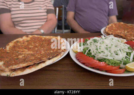 Two Pieces Of Lahmacun And Traditional Salad Served To Customers On Wooden Table Stock Photo