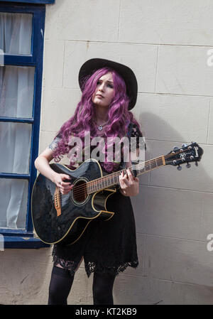 A young girl singing anjd playing the guitar at Whitby,North Yorkshire,England,UK Stock Photo