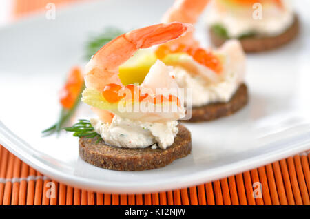 Tidbits with prawns, spiced cream cheese, salmon caviar and dill Stock Photo