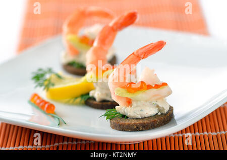 Tidbits with prawns, spiced cream cheese, salmon caviar and dill Stock Photo