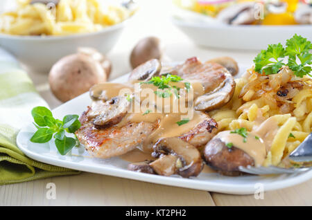 Escalope of pork with champignons, sauce and spaetzle served on a white on a white plate Stock Photo