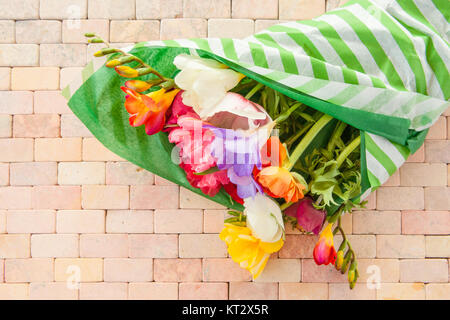 Bunte Fruehlingsblumen auf rustikalem Hintergrund aus Steinfliesen