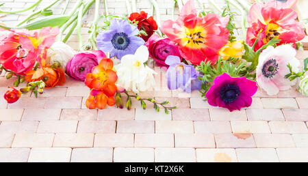 Bunte Fruehlingsblumen auf rustikalem Hintergrund aus Steinfliesen
