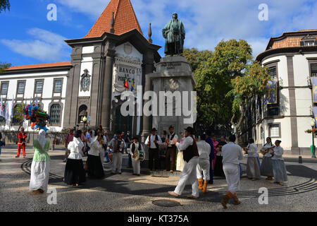 Group of folk musicians and folk dancers performing on the Avenida Arriaga with the iconic Bank of Portugal in the background, Funchal, Madeira. Stock Photo