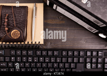 Top view of a vintage notebook next to a pile of folders and a computer keyboard Stock Photo