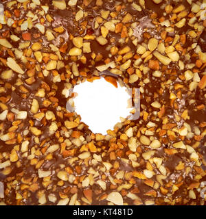 Overfill milk chocolate doughnut close-up with crushed nuts on white background Stock Photo