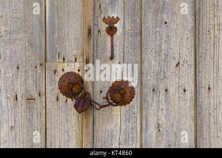 Close up of rusty old iron mountings with chain and padlock on a vintage wooden double door, Greece. Stock Photo
