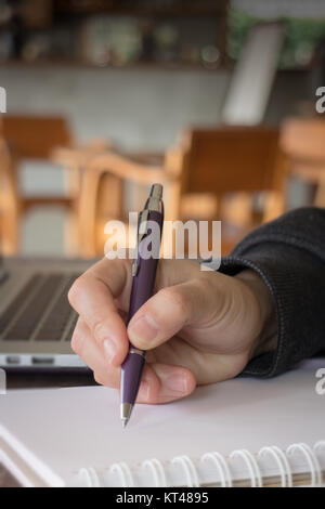 Woman hand writing on noteboook paper Stock Photo