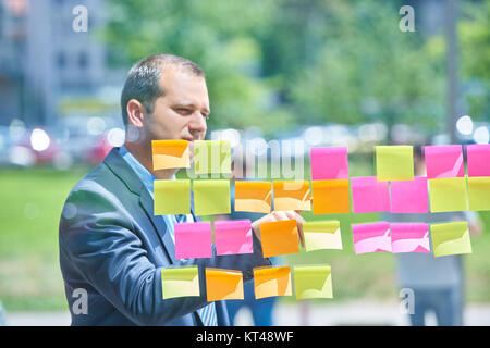businesspeople discussing and planning concept. Front of glass wall marker and stickers. Startup office. Stock Photo