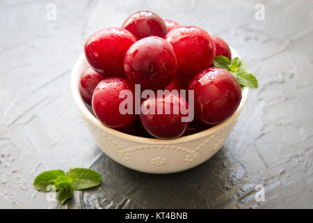 Delicious red plums in a wooden bowl, selective focus Stock Photo