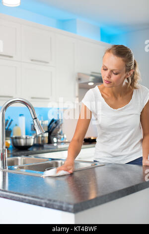 Pretty, young woman in her modern, clean and bright kitchen, cleaning the kitchen (color toned imagey  shallow DOF) Stock Photo