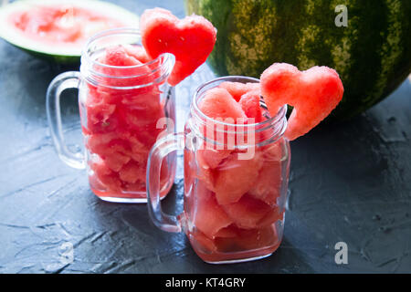Watermelon in Mason jars decorated with watermelon slices curved like heart symbols Stock Photo