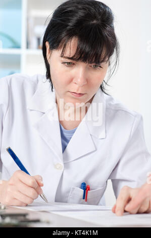 Scientist or a medic in a white coat making notes Stock Photo