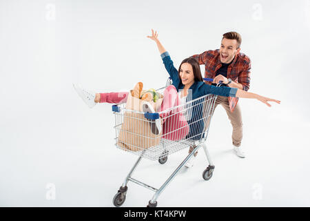 Happy young man pushing shopping cart with excited young woman and grocery bag Stock Photo