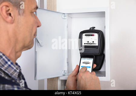 Technician Doing Meter Reading Using Mobilephone Stock Photo