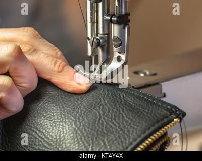 Sewing machine in action in workshop operated with hands working on garment Stock Photo