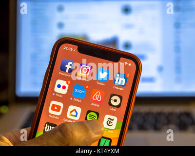 NEW YORK, USA - NOVEMBER 7, 2017: Social media app icons on new smartphone display close-up around other iphone applications with laptop in background Stock Photo