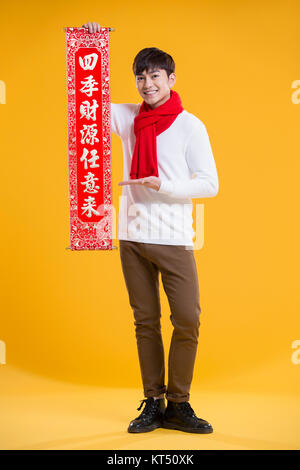 Cheerful young man celebrating Chinese New Year with couplet Stock Photo