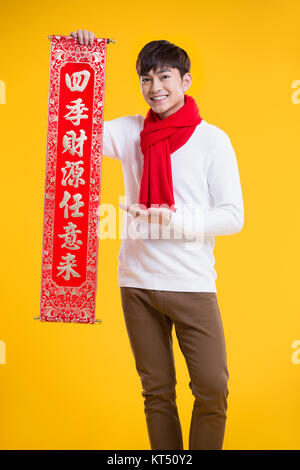 Cheerful young man celebrating Chinese New Year with couplet Stock Photo