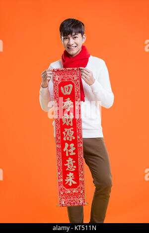 Cheerful young man celebrating Chinese New Year with couplet Stock Photo