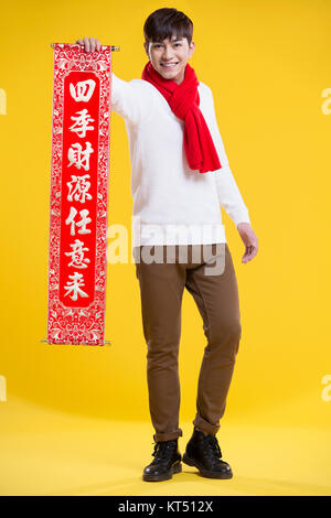 Cheerful young man celebrating Chinese New Year with couplet Stock Photo