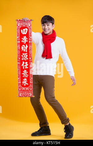 Cheerful young man celebrating Chinese New Year with couplet Stock Photo