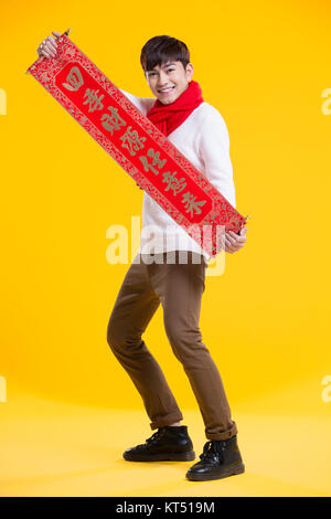 Cheerful young man celebrating Chinese New Year with couplet Stock Photo