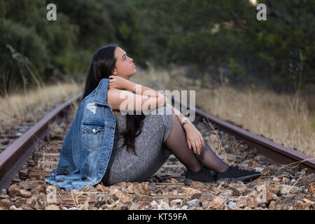 Young woman sitting on the train track