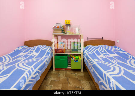 The interior of a small dorm room with two beds and a homemade rack in the middle Stock Photo