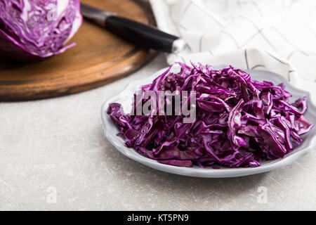 Shredded red cabbage in clay bowl on stone background. Vegetarian healthy food. Stock Photo