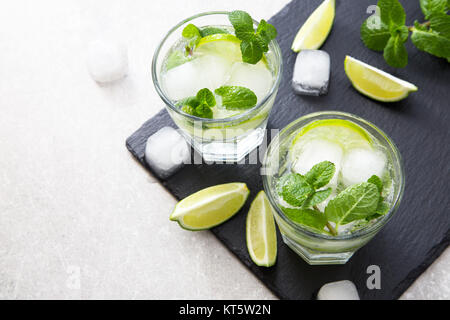 Cold refreshing summer lemonade mojito in a glass on a slate board and stone background. Stock Photo