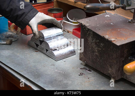Ingots of melted alloy arranged in a pyramid on the workshop table. Stock Photo