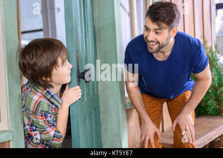 side view of smiling father and son playing hide and seek at home Stock Photo