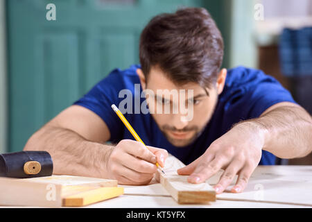portrait of concentrated carpenter working taking measures of wooden plank Stock Photo
