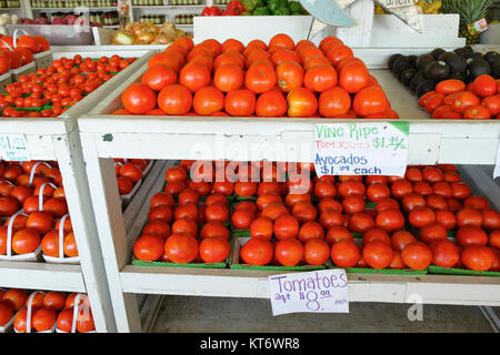 Farmer's market or produce market or stand with beefsteak, roma and cherry tomatoes for sale along with avocados and other fruits and vegetables. Stock Photo