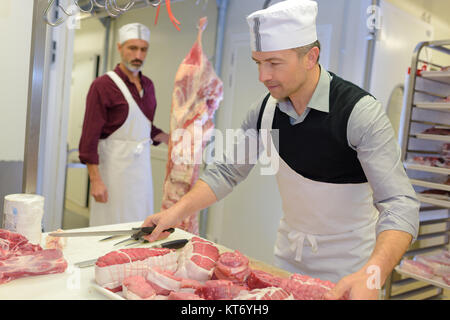 Butcher lifting tray of meat Stock Photo