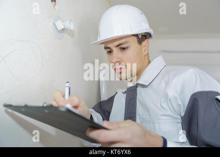 male engineer writing on clipboard at construction site Stock Photo
