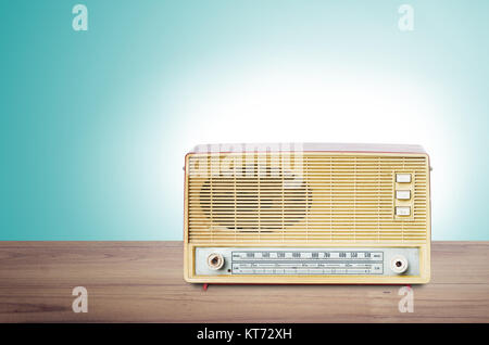 Old dusty radio from 1970 on wooden table with mint green background. Stock Photo