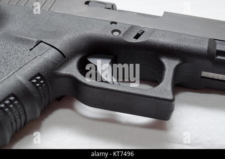 A close up of a black semi automatic pistol, showing the trigger, trigger guard, grip and ejection port Stock Photo