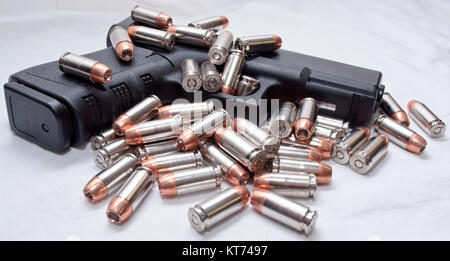 A black semi automatic pistol with .40 caliber hollow point bullets laying on the gun and next to it. Shot with a white background Stock Photo