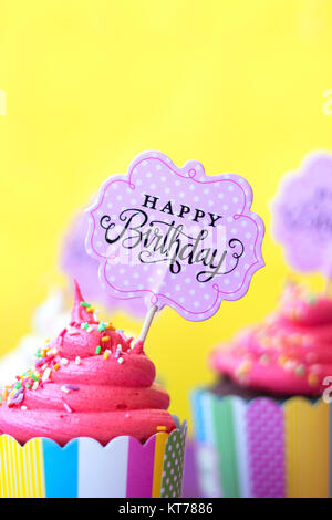 Tasty strawberry cupcakes with Happy Birthday greeting card on yellow background. Party background Stock Photo