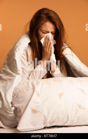 illness flu - Young Woman Lying On Bed Infected With Allergy Blowing Her Nose Stock Photo