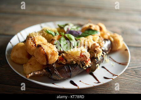 Delicious restaurant dish,includes fried potato with cheese and grille vegetables. Tasty appetizer decorated with fresh mint leaves and sauce. Stock Photo