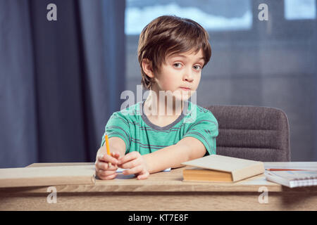 portrait of boy sitting at table and doing homework at home Stock Photo