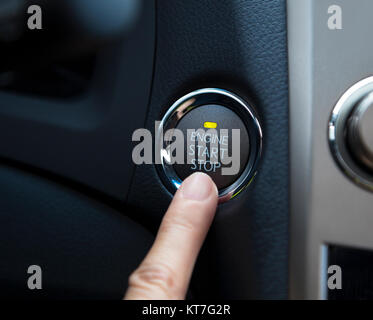 finger pressing the Engine start stop button of a car Stock Photo