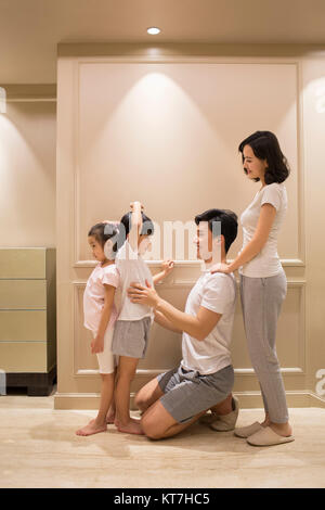 Cheerful young parents measuring their children's height Stock Photo