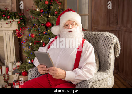 Santa Claus using digital tablet Stock Photo
